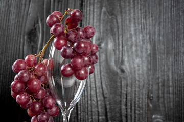Bunch of red grapes and champagne glass with dark wood background