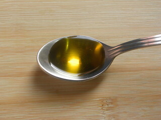 Golden yellow color Mustard oil on stainless steel spoon