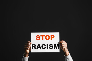 African-American man with poster on dark background. Stop racism