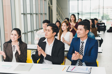 Asian male speaker is speaking at seminars and workshops to the people in the meeting. Attendees applaud the speaker when the meeting is finished