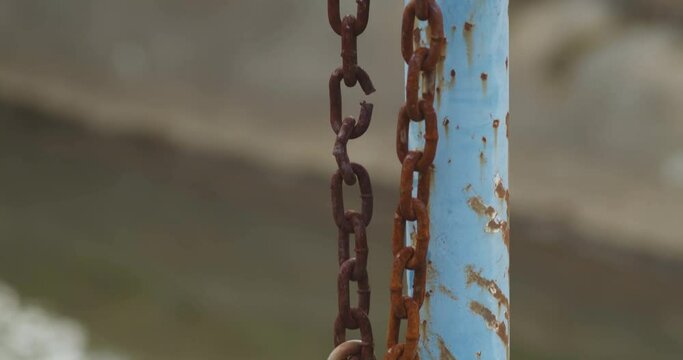 Rusty Brown Chain Hanging Down Blue Iron Fence Post