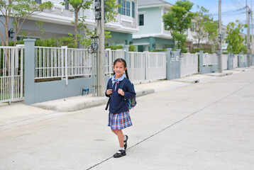 Cheerful asian little child girl in kindergarten uniform walking on street leave home to go to school at morning