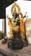 Estatua del dios Ganesha de color dorado y con guirnaldas de flores
