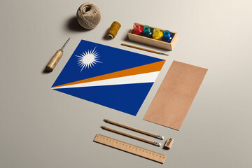 Fototapeta na wymiar Marshall Islands calligraphy concept, accessories and tools for beautiful handwriting, pencils, pens, ink, brush, craft paper and cardboard crafting on wooden table.