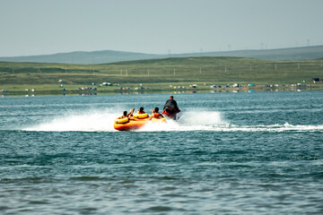 A jet ski pulls an inflatable raft with people on the water. A fun adventure at speed.