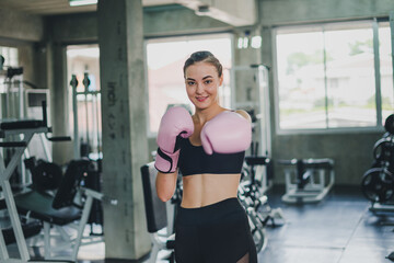 Naklejka na ściany i meble Beautiful girls exercise by boxing in the gym. She wears a pink boxing glove and wears exercise.