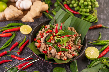 Stir-fried pork basil on banana leaves in a frying pan.