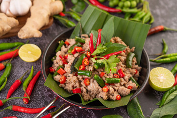 Stir-fried pork basil on banana leaves in a frying pan.