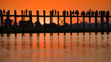 Silhouette of people walking during sunset at U Bein Bridge, Mandalay, Myanmar.