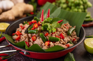 Stir-fried pork basil on banana leaves in a frying pan.