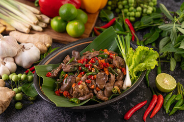 Stir-fried chicken liver basil on banana leaves in a black dish