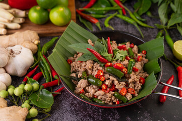 Stir-fried pork basil on banana leaves in a frying pan.