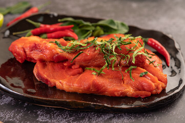Marinated pork used in cooking, complete with chili peppers Kaffir lime leaves in a black plate