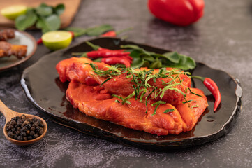 Marinated pork used in cooking, complete with chili peppers Kaffir lime leaves in a black plate