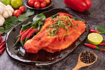 Marinated pork used in cooking, complete with chili peppers Kaffir lime leaves in a black plate