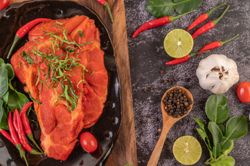 Marinated pork used in cooking, complete with chili peppers Kaffir lime leaves in a black plate
