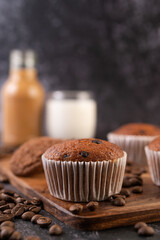 Banana cupcakes that are placed on a wooden plate with coffee grains.