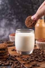 Milk in a glass, complete with coffee beans, cupcakes, bananas and cookies on a wooden plate.