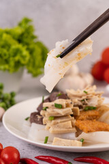 Large noodle noodles with pork blood sausage, crispy pork slices, and sliced ​​onions in a...