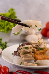 Large noodle noodles with pork blood sausage, crispy pork slices, and sliced ​​onions in a white plate.