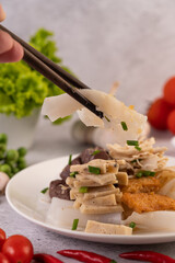 Large noodle noodles with pork blood sausage, crispy pork slices, and sliced ​​onions in a...