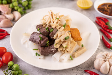 Large noodle noodles with pork blood sausage, crispy pork slices, and sliced ​​onions in a white plate.