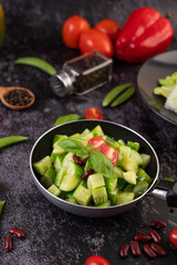 Cucumber stir-fried with tomatoes and red beans in a frying pan.