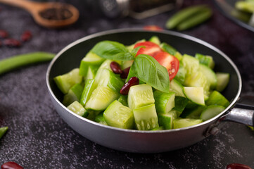 Cucumber stir-fried with tomatoes and red beans in a frying pan.