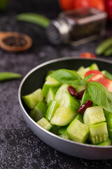 Cucumber stir-fried with tomatoes and red beans in a frying pan.