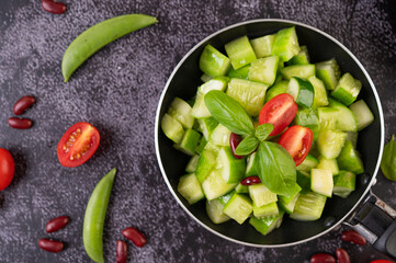 Cucumber stir-fried with tomatoes and red beans in a frying pan.
