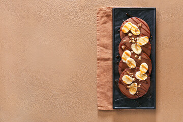 Plate with delicious chocolate pancakes on color background
