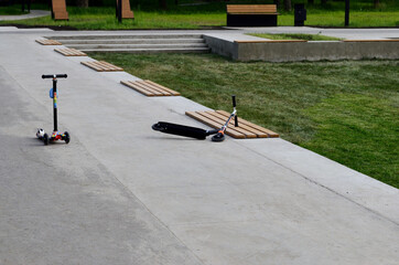 two scooters one stands the other lies on the track in the park around no people