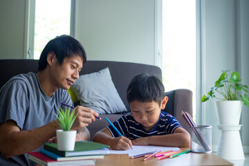 Asian father and son enjoy painting at home. Family activities and study at home concept