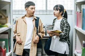 Obraz premium Men and women carrying a backpack and searching for books in the library.