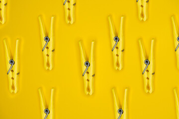 Flat lay of clothes pegs isolated on a yellow background