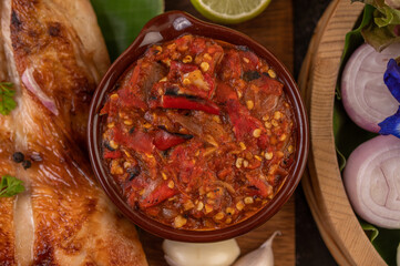 Grilled chicken on a plate with chili peppers, garlic sauce and sprinkled with pepper seeds.