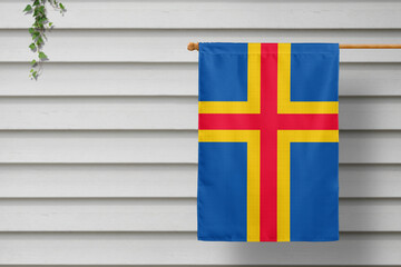 Aland Islands national small flag hangs from a picket fence along the wooden wall in a rural town....