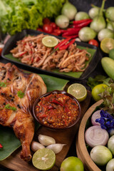 Grilled chicken on a plate with chili peppers, garlic sauce and sprinkled with pepper seeds.