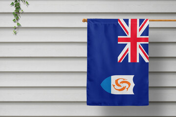Anguilla national small flag hangs from a picket fence along the wooden wall in a rural town. Independence day concept.