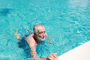 happy elderly caucasian swimming in pool during retirement holiday with relaxation and smiling