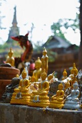 Estatuas de Buda de diferentes tamaños color dorado , fondo desenfocado, templo de Tailandia