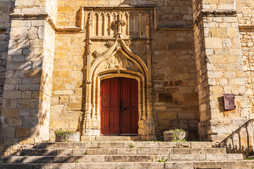 Fototapeta na wymiar Red door of the Church of St. Thomas in Excideuil.