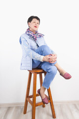 portrait of a cheerful senior woman sitting over background