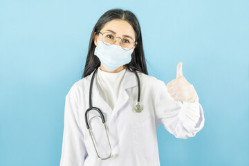 Smart young asian female doctor in lab coat with Medical face mask,white latex medical gloves and stethoscope against blue background,health care concept