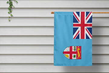 Fiji national small flag hangs from a picket fence along the wooden wall in a rural town. Independence day concept.
