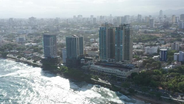 Majestic flight over the Caribbean Sea highlighting the Malecon de Santo Domingo on a sunny day and moderate waves.