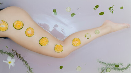 Orange rings on a female leg in a bath with milk. Skin care