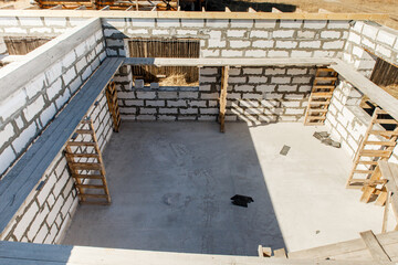 Building site of a house under construction. Unfinished house walls made from white aerated autoclaved concrete blocks. Scaffolding for workers assembled from boards and Euro-pallets. top view