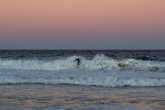 "Maroubra Beach, NSW / Australia - 5th July 2020" Surfer catching waves at sunset, beautiful pink coloured sunset