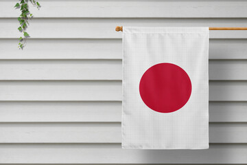 Japan national small flag hangs from a picket fence along the wooden wall in a rural town. Independence day concept.